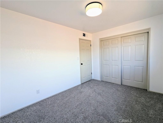 unfurnished bedroom with carpet floors, a closet, and visible vents