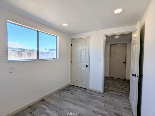 unfurnished bedroom featuring baseboards, wood finished floors, and recessed lighting