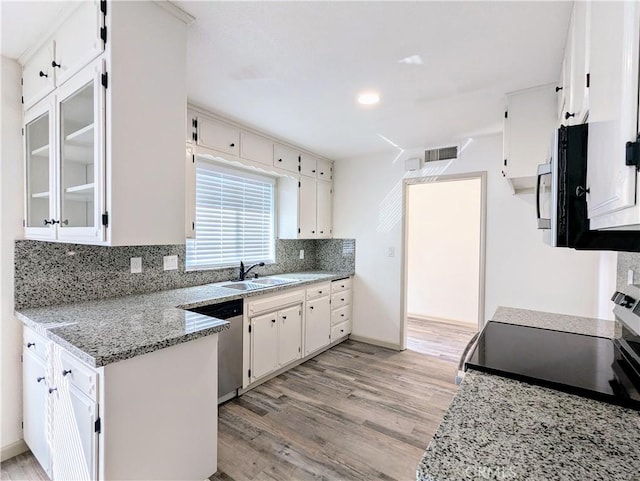 kitchen with light wood finished floors, white cabinets, decorative backsplash, appliances with stainless steel finishes, and a sink