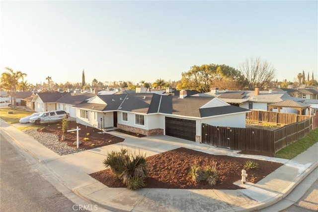 view of front of property featuring a garage, concrete driveway, fence, and a residential view