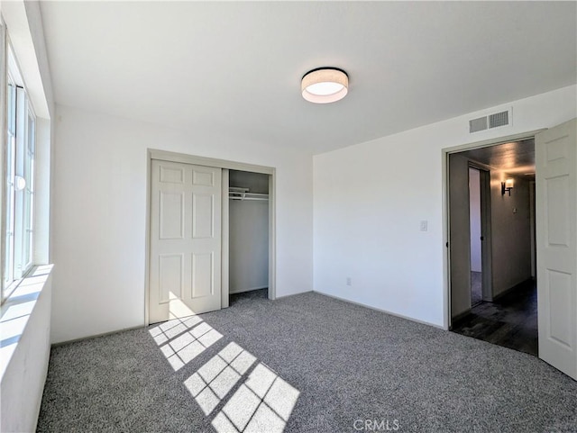 unfurnished bedroom featuring carpet floors, a closet, and visible vents