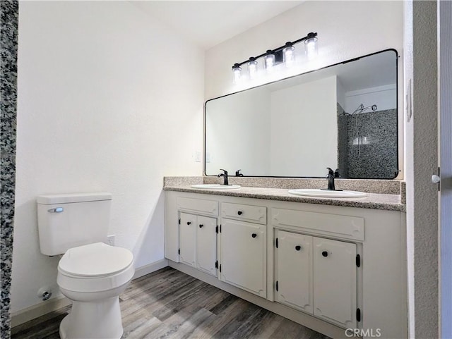 full bathroom with double vanity, a sink, toilet, and wood finished floors