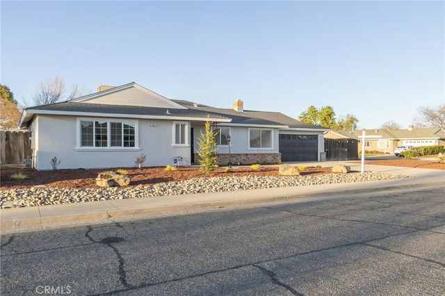 single story home with concrete driveway, an attached garage, and fence