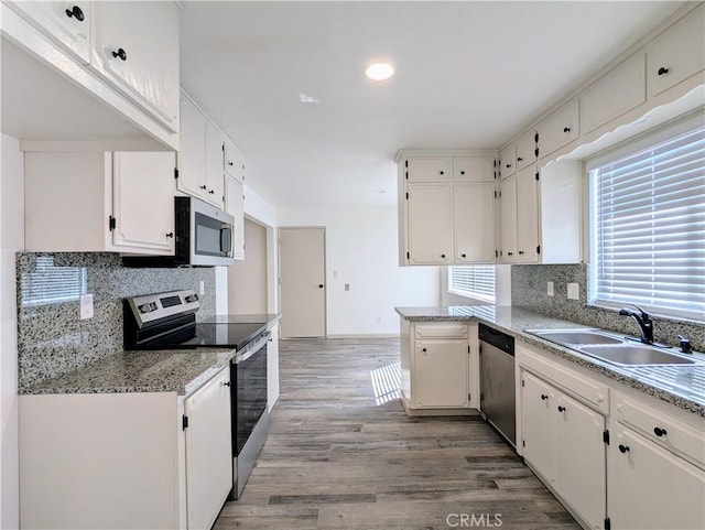 kitchen featuring light wood-style flooring, appliances with stainless steel finishes, tasteful backsplash, and a sink