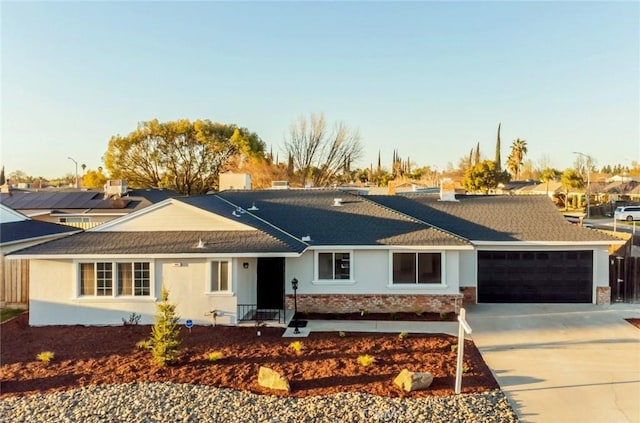 ranch-style house featuring brick siding, a shingled roof, concrete driveway, an attached garage, and stucco siding