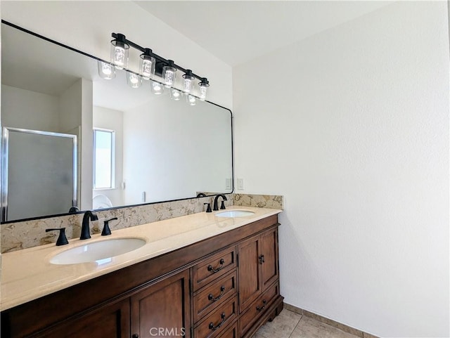 bathroom with double vanity, a shower stall, a sink, and tile patterned floors