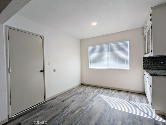 unfurnished dining area featuring light wood-style flooring and baseboards