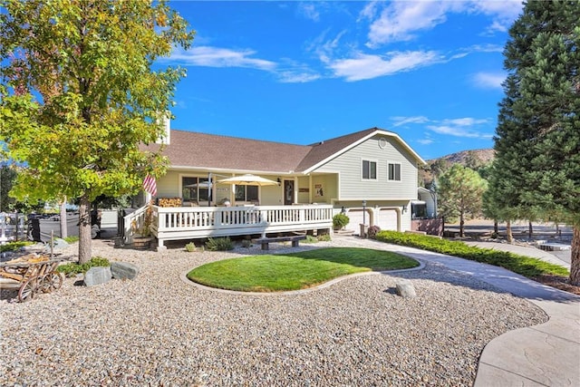 back of house with a deck, a lawn, concrete driveway, and a garage