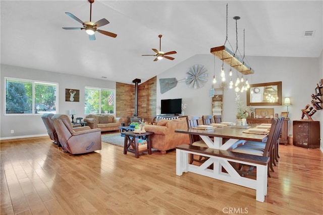 living room featuring light wood-style flooring, a ceiling fan, visible vents, and a wood stove