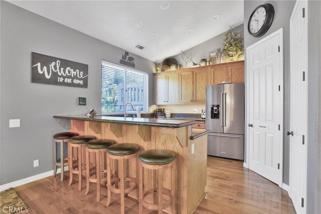 kitchen with visible vents, a breakfast bar, a peninsula, dark countertops, and high quality fridge