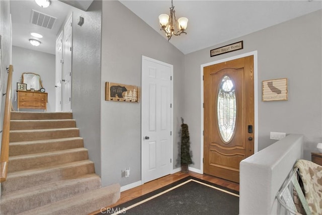 foyer entrance with visible vents, stairway, baseboards, and an inviting chandelier