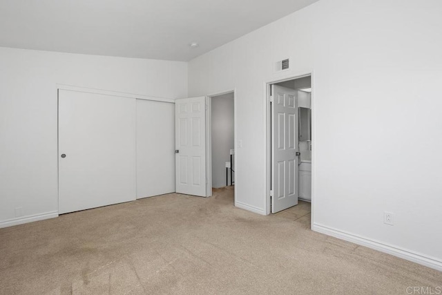 unfurnished bedroom with lofted ceiling, visible vents, baseboards, a closet, and carpet