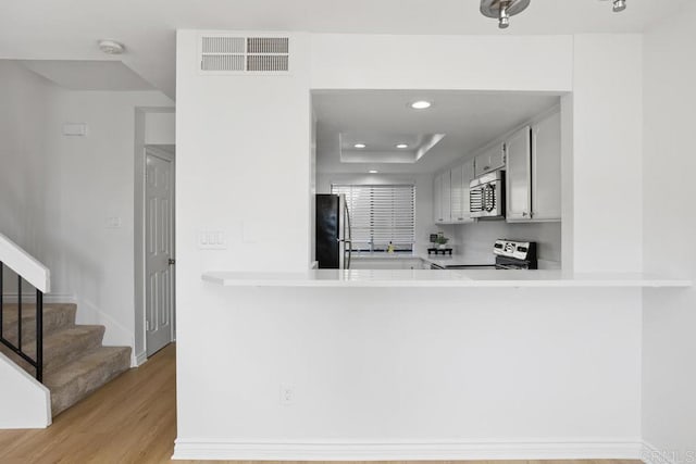 kitchen with stainless steel appliances, recessed lighting, light countertops, visible vents, and light wood-style flooring