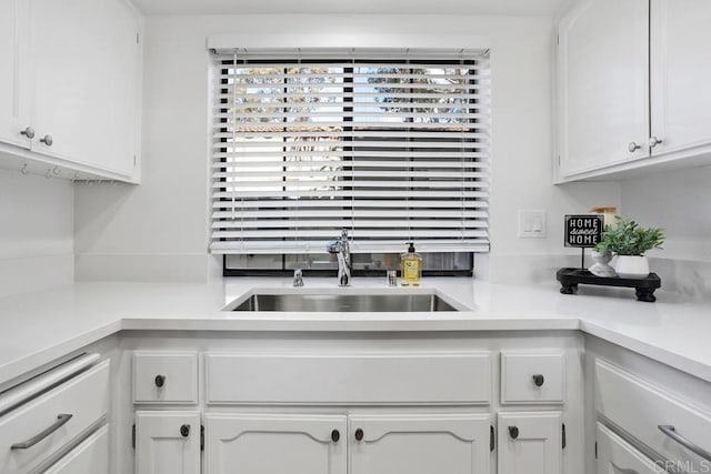 kitchen with light countertops, white cabinets, and a sink