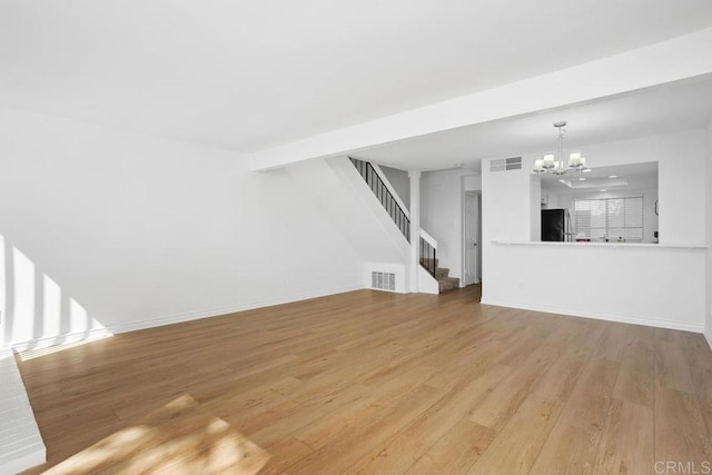 unfurnished living room featuring visible vents, light wood-style floors, a chandelier, baseboards, and stairs