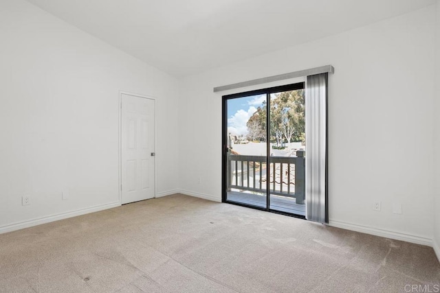 carpeted empty room featuring lofted ceiling and baseboards