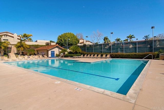 pool with a patio area and fence