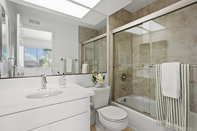 bathroom with a skylight, visible vents, toilet, enclosed tub / shower combo, and vanity