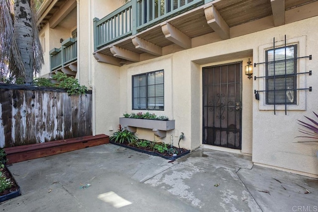 doorway to property featuring a patio, fence, and stucco siding