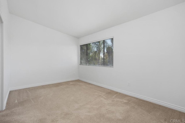 empty room with lofted ceiling, carpet, and baseboards