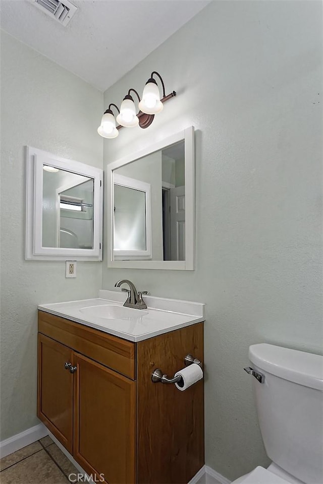 bathroom featuring vanity, visible vents, baseboards, tile patterned flooring, and toilet