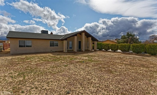 back of property featuring stucco siding, cooling unit, a chimney, and fence