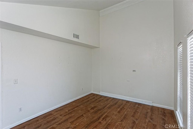 spare room featuring visible vents, baseboards, and wood finished floors