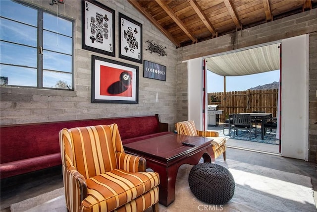 sitting room featuring lofted ceiling with beams, concrete floors, wood ceiling, and a healthy amount of sunlight