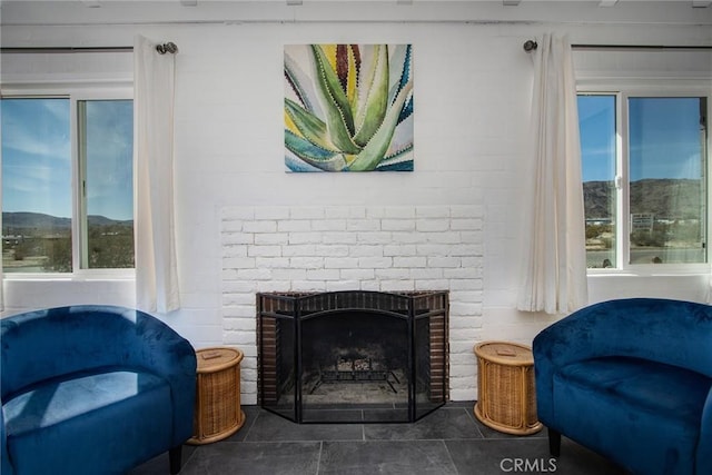 sitting room with a healthy amount of sunlight, a brick fireplace, and a mountain view