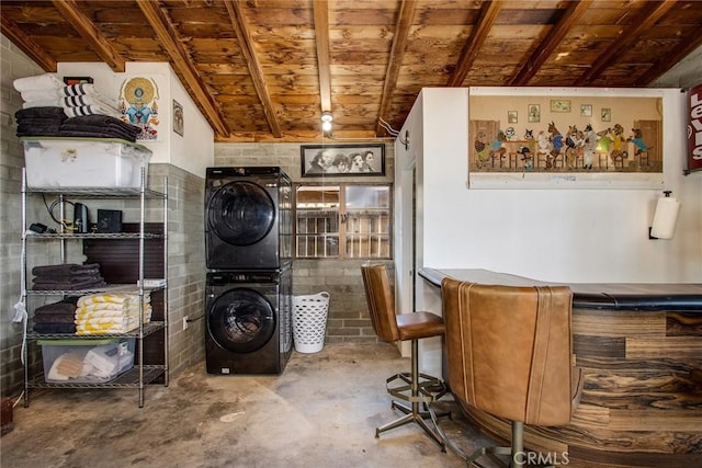 interior space with concrete flooring, a dry bar, stacked washer / dryer, and wooden ceiling