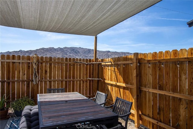 view of patio / terrace featuring fence, a mountain view, and outdoor dining space