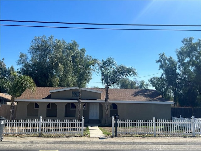 ranch-style house featuring a fenced front yard and stucco siding