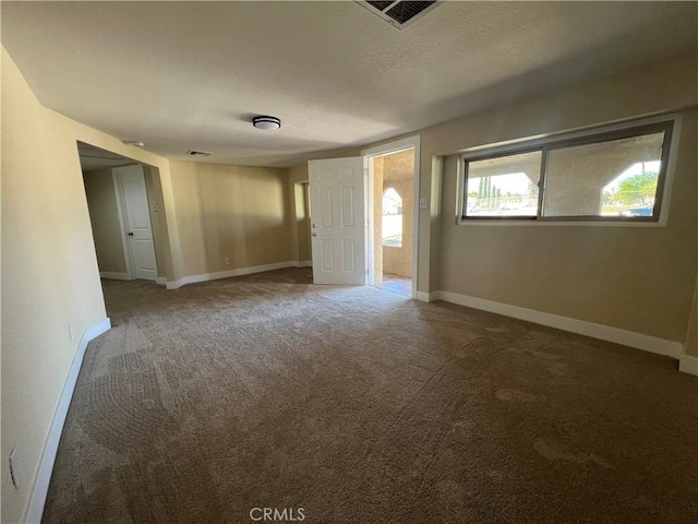 carpeted spare room featuring baseboards, visible vents, and a textured ceiling