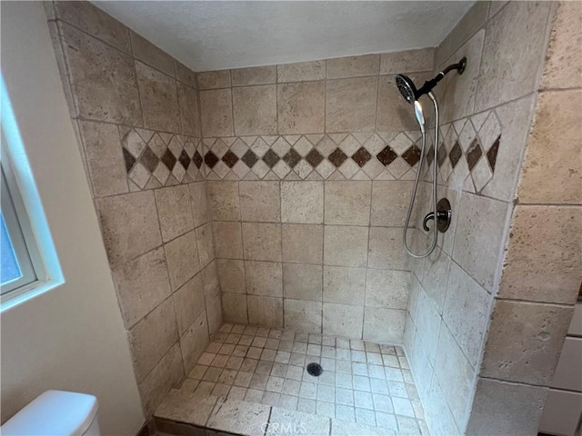 bathroom featuring toilet and tiled shower