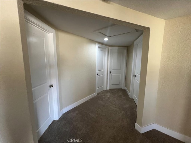 corridor with baseboards, carpet flooring, and a textured wall