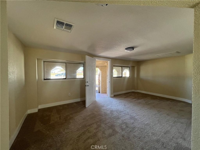 carpeted spare room featuring visible vents, baseboards, and a textured ceiling