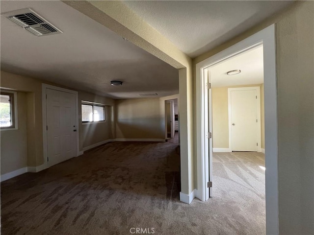 hallway featuring visible vents, baseboards, and carpet floors