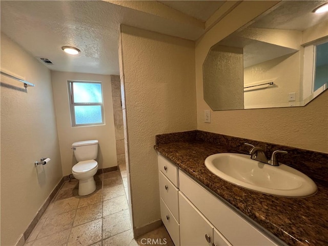 bathroom featuring visible vents, toilet, a textured ceiling, baseboards, and vanity