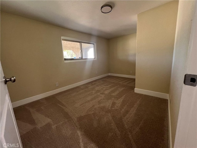 carpeted spare room featuring baseboards