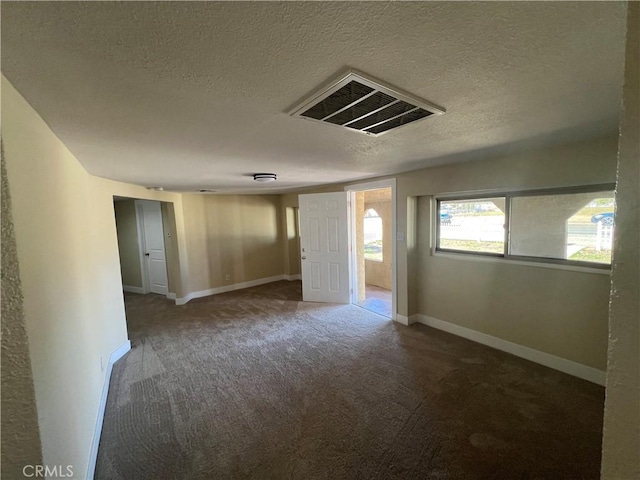 empty room featuring visible vents, baseboards, a textured ceiling, and carpet