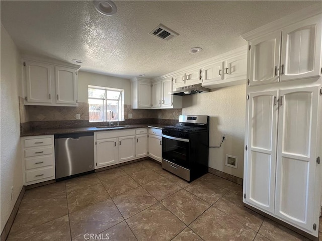 kitchen featuring dark countertops, visible vents, stainless steel appliances, and a sink