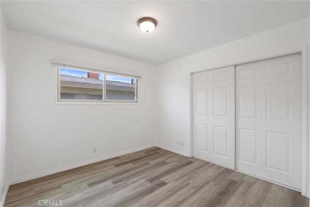 unfurnished bedroom featuring a closet, wood finished floors, and baseboards