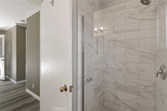 bathroom with baseboards, a stall shower, wood finished floors, and crown molding