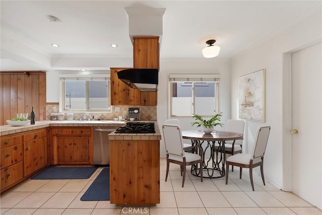 kitchen featuring brown cabinets, crown molding, tile counters, backsplash, and dishwasher