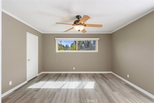 empty room with baseboards, light wood finished floors, and crown molding