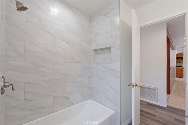 full bathroom with baseboards, visible vents, wood finished floors, and shower / bathing tub combination