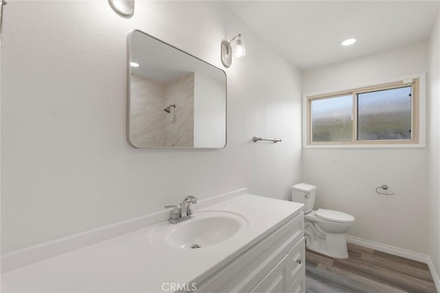 bathroom featuring toilet, wood finished floors, vanity, baseboards, and a shower