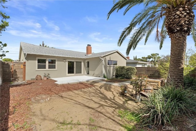 rear view of property featuring a patio area, fence, a chimney, and stucco siding