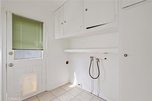 clothes washing area with hookup for a washing machine, light tile patterned floors, and cabinet space