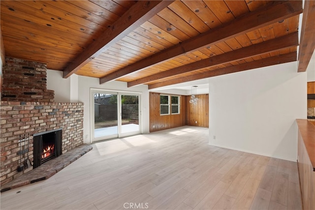 unfurnished living room with wooden ceiling, a brick fireplace, wood finished floors, and beamed ceiling